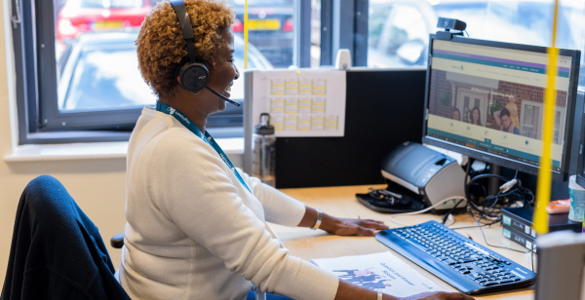 A female member of staff sat at her desk, helping a resident on the phone. 