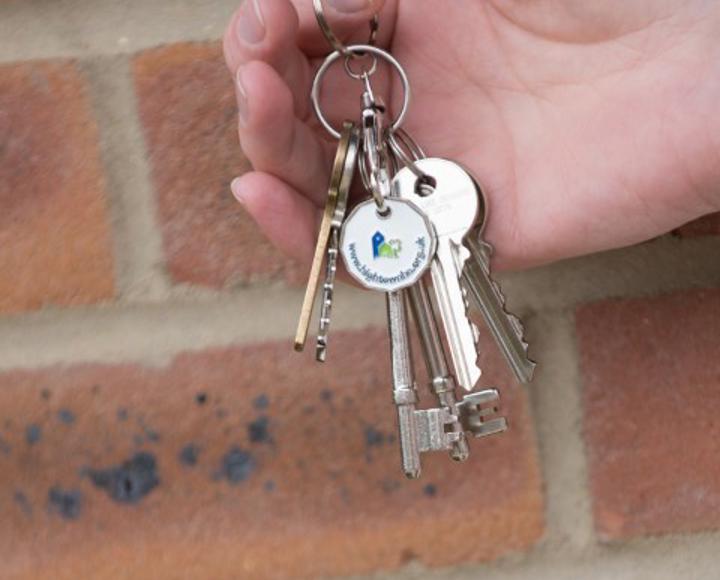 someone holding a set of keys in front of a brick wall