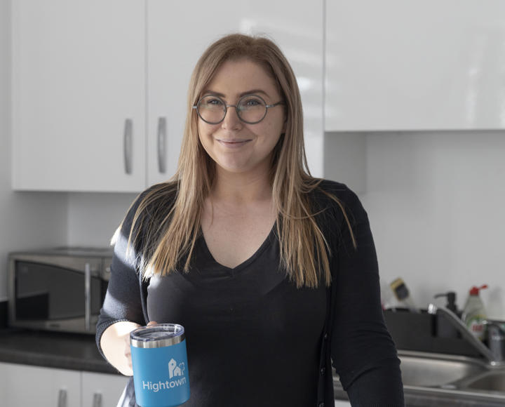 A Hightown resident stood in her kitchen with a blue Hightown branded mug.