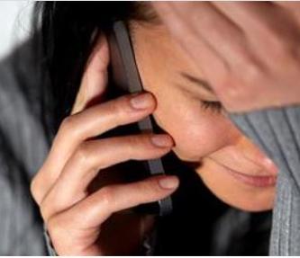 A woman speaking on her mobile phone. She is distressed with her hand on her forehead.