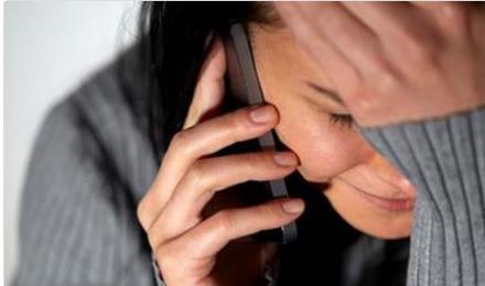 A woman speaking on her mobile phone. She is distressed with her hand on her forehead.