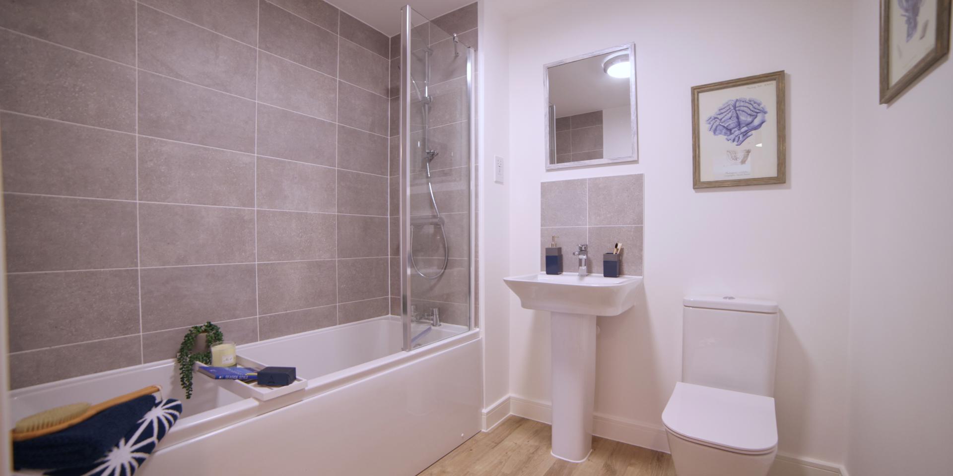 The bathroom has a white suite with a shower over the bath and a pedestal sink and w/c. There is also a glass shower screen