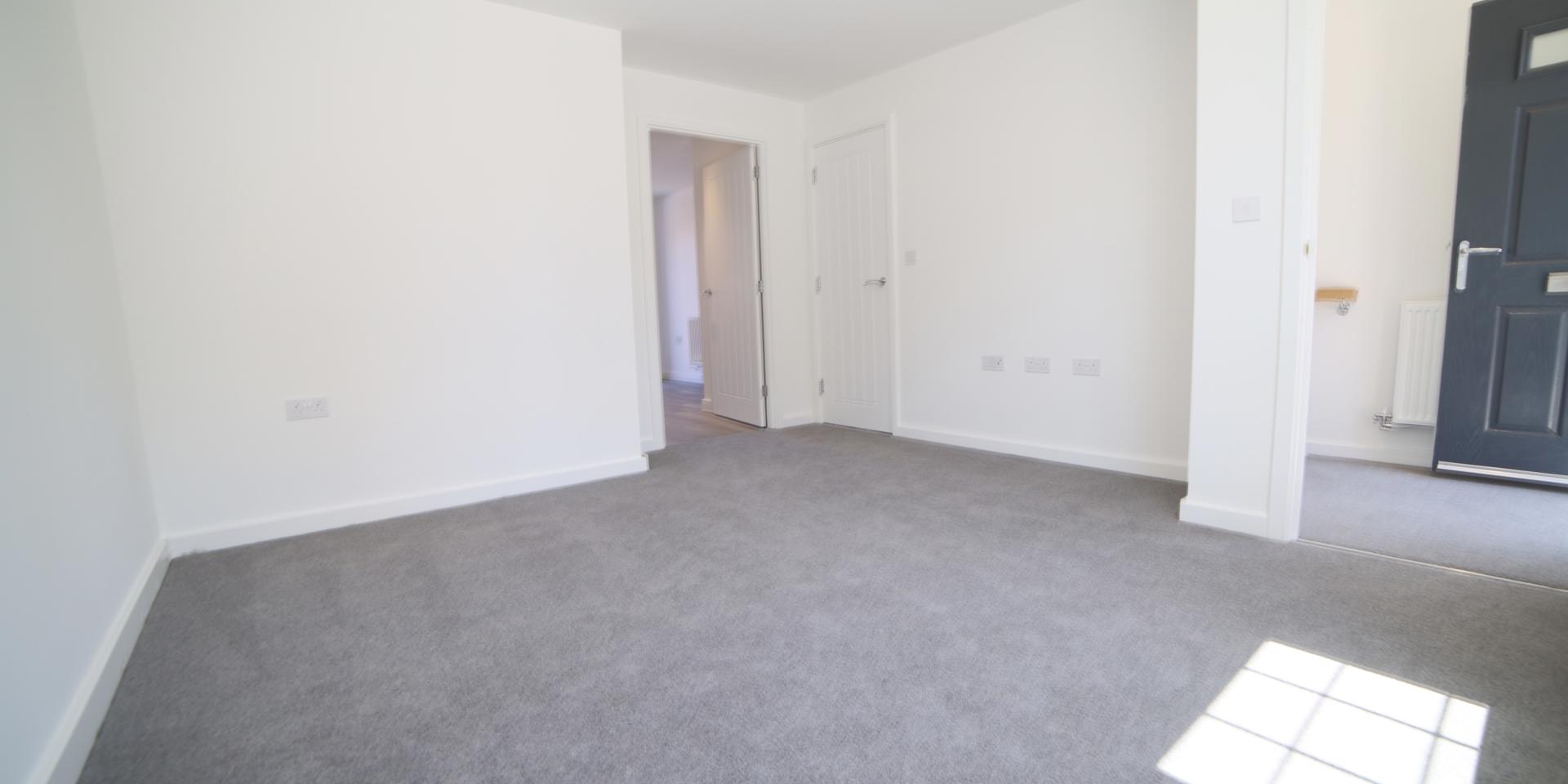 The living room has a grey carpet and is situated at the front of the house