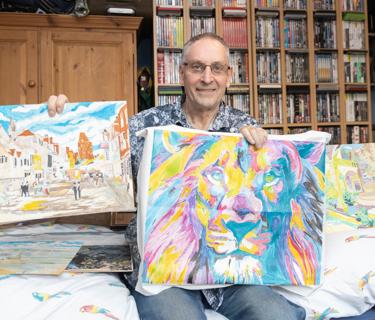 Hightown service user shows his colourful painting of a lion, amongst other paintings