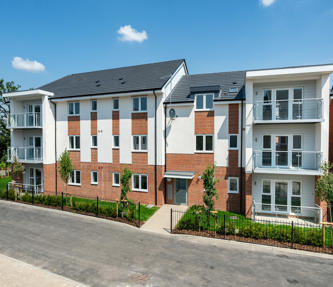 A new block of flats taken on a sunny day. Light brick work and some of it is painted white. Some have glass balconies. 