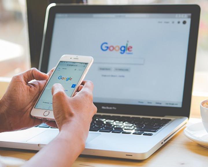 Someone googling for contacts on their phone and laptop