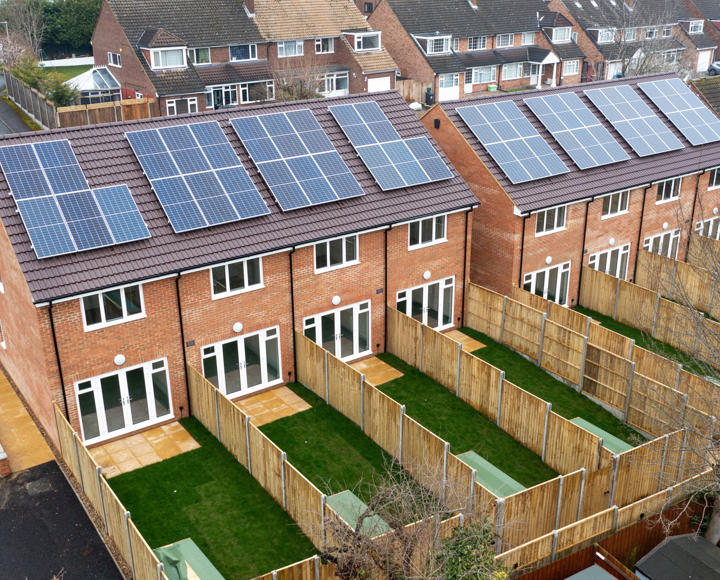 The back of a row of houses, showing each individual back gardens. Each house has a solar panel.