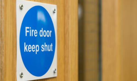 A sign on a wooden door which reads 'fire door keep shut'.