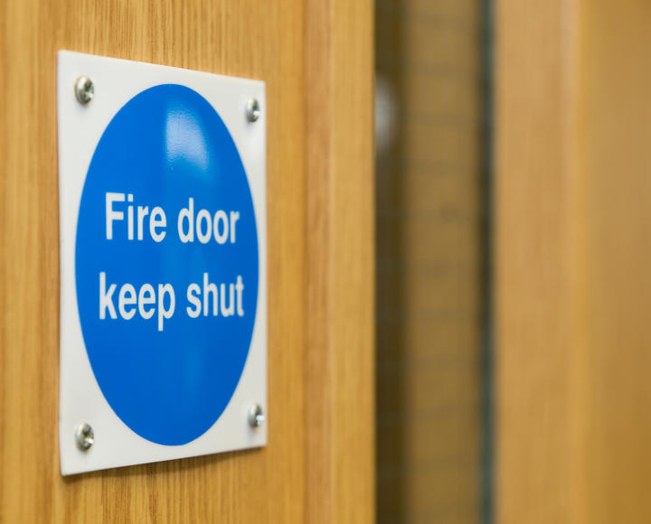 A sign on a wooden door which reads 'fire door keep shut'.