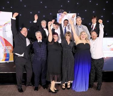 Staff and service users celebrating winning an award, dressed up in black tie