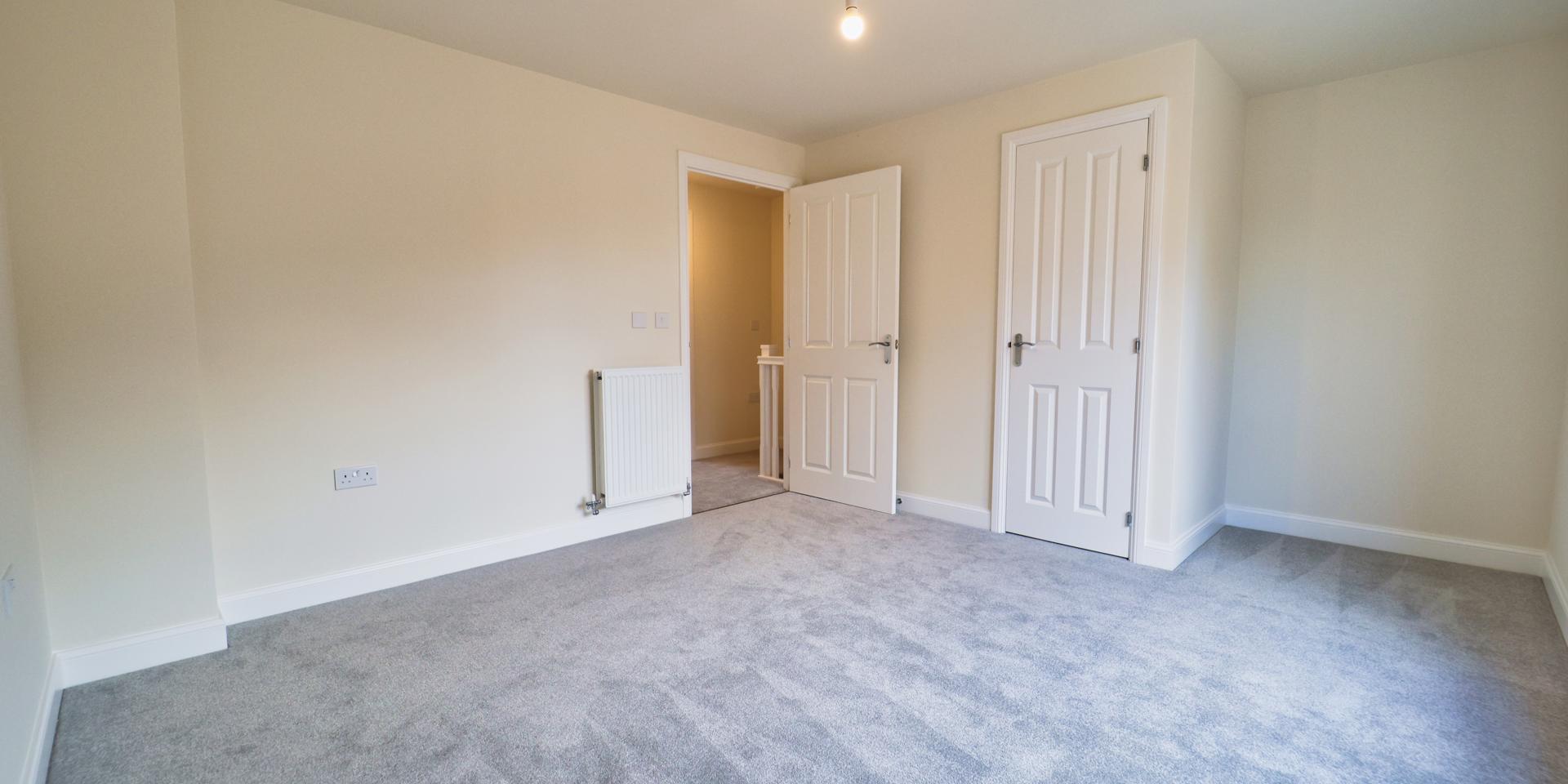 A good sized double bedroom with built-in storage cupboard and grey carpet