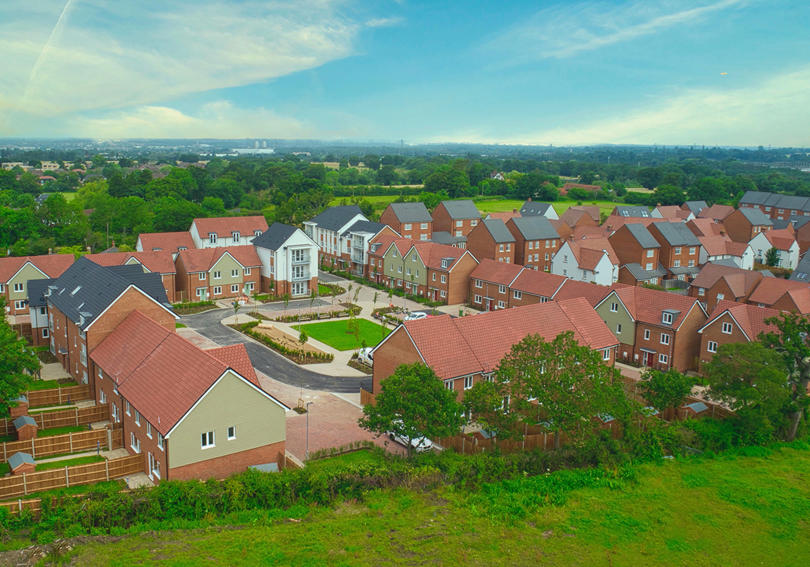 A communal grass area surrounded by houses, which each have their own garden.