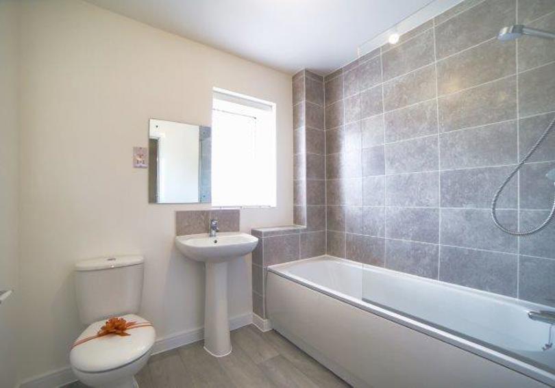 Image of the bathroom including the shower over the bath, wash hand basin and toilet