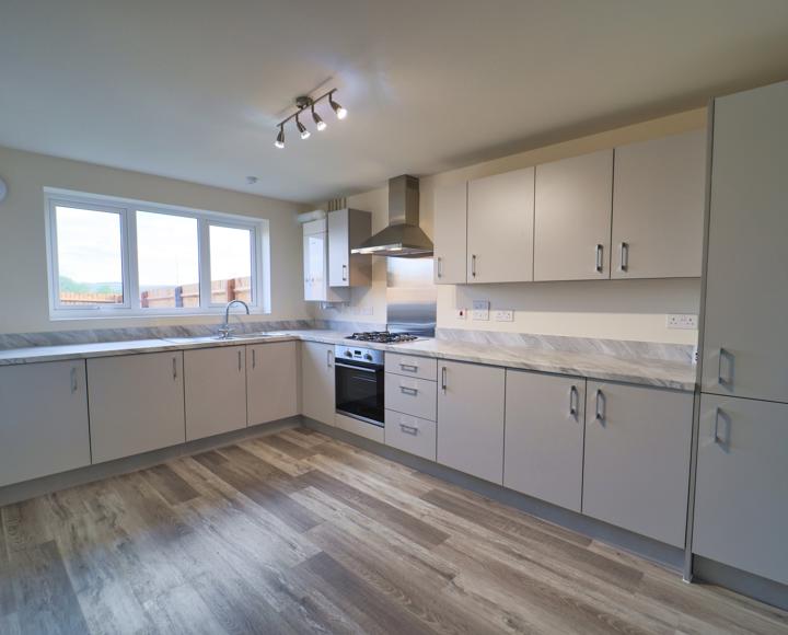 A large kitchen with plenty of wall and floor units, integrated appliances and vinyl flooring