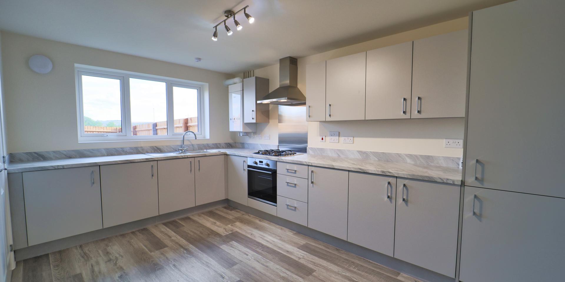 A large kitchen with plenty of wall and floor units, integrated appliances and vinyl flooring