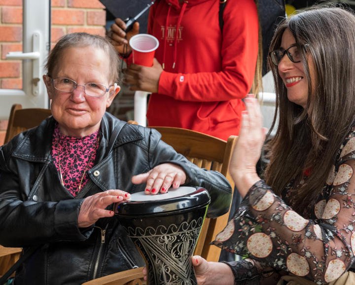 Two women playing bongo drums and smiling