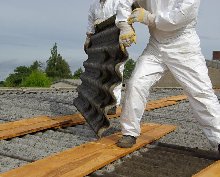 Two people moving roofing which has asbestos in