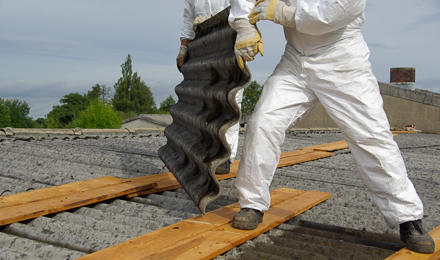 Two people moving roofing which has asbestos in