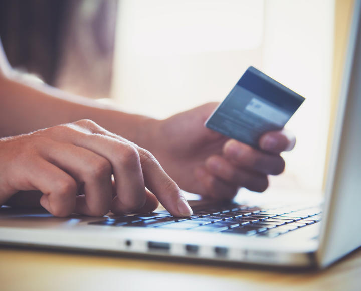 Someone on a laptop with their debit card paying rent