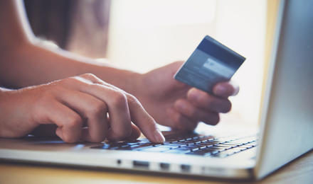Someone on a laptop with their debit card paying rent