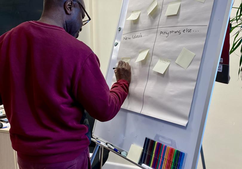 A Hightown staff member writing suggestions on a 'tell us what you think' EDI board 