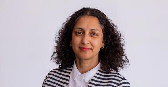 Headshot of Charmaine De Souza - member of the board at Hightown. She is wearing a black and white stripped cardigan and has brown curly hair and brown eyes.