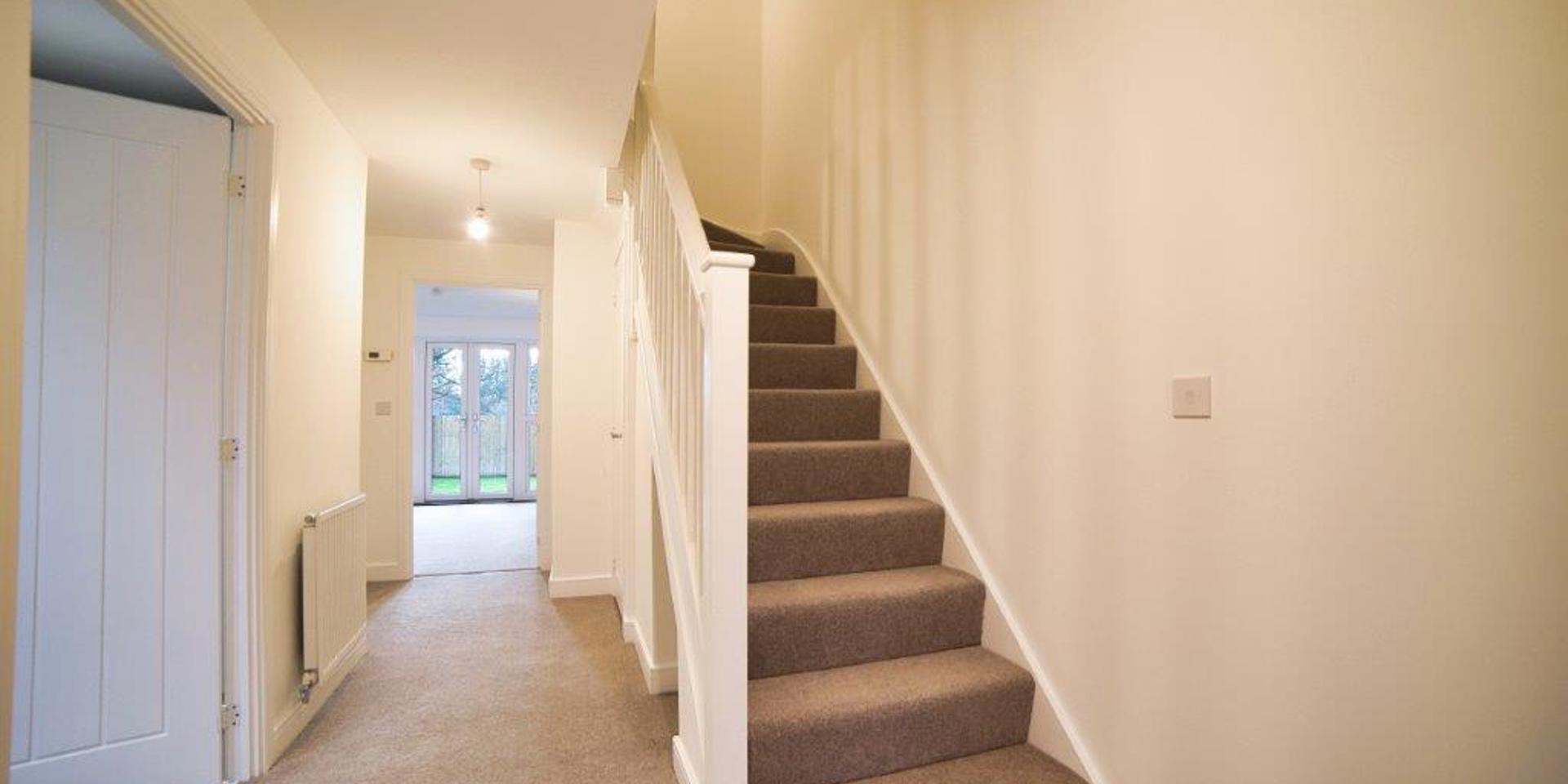 Photo taken from inside the front door showing the bottom of the stairs, hallway and doorway into the living room
