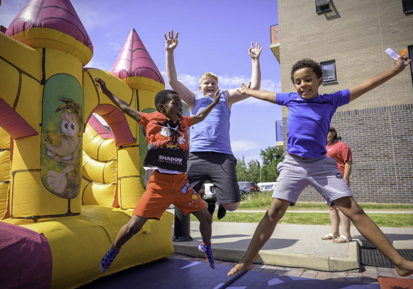 Three children jumping next to inflatable slide