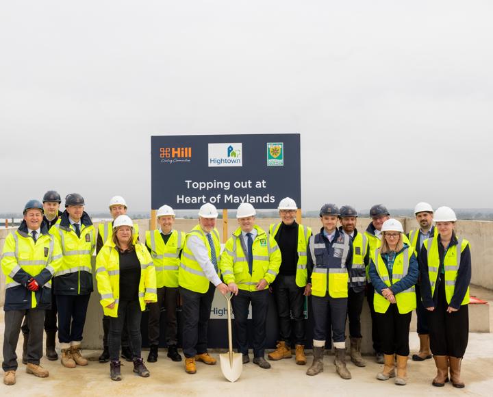 Hightown staff and stakeholders in hi-vis jackets and hard hats and the MP is holding a shovel