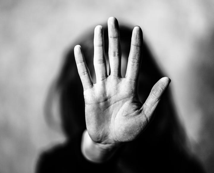 A woman with her hand in front of her face, signally to stop
