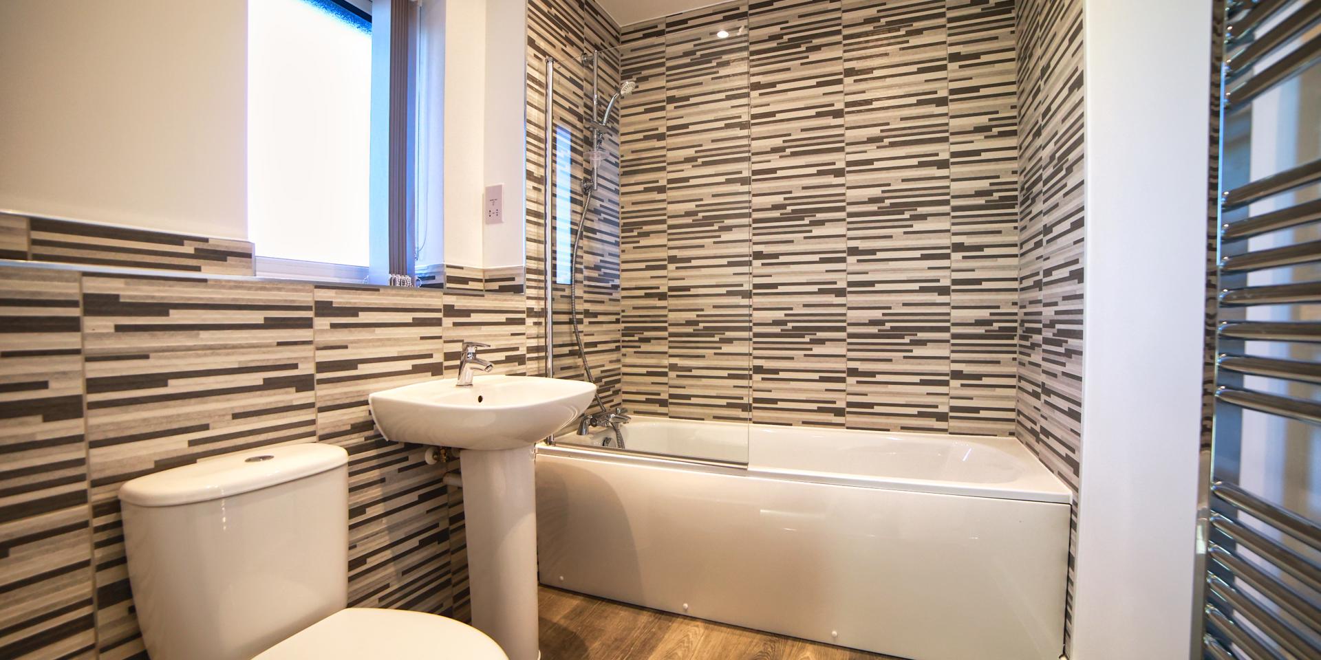 The bathroom has a white suite and bath with thermostatic shower