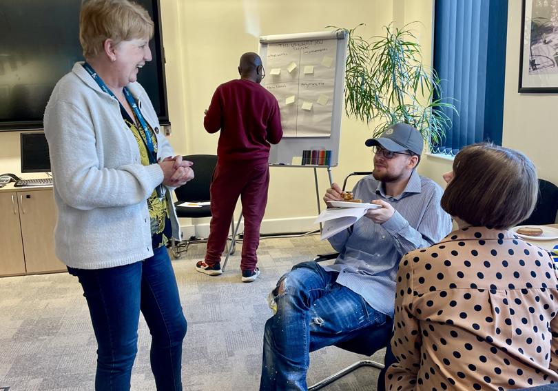 A resident talking to Hightown staff members at an EDI event at Hightown house. The resident has food and refreshments.
