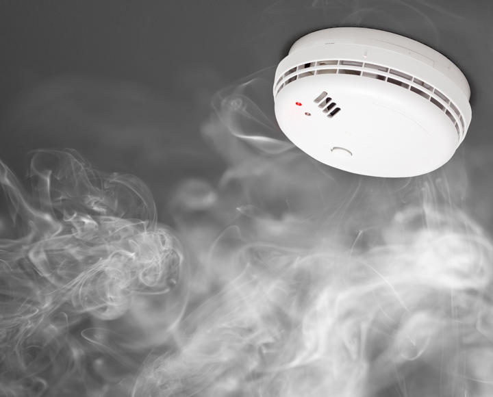A smoke alarm on a ceiling with lots of smoke around it.