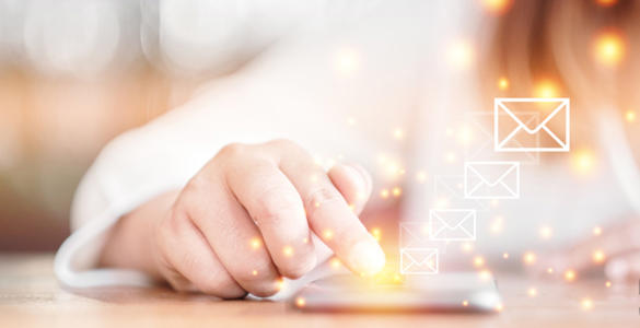 A woman using her mobile phone on a table. Email icons are shown, she's looking at her emails.