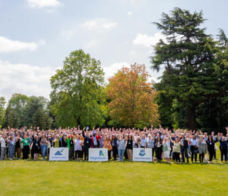 Hightown staff waving outside with Hightown logo and sign saying 'Building homes. Supporting people.'