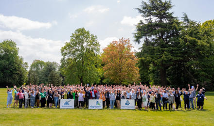 Hightown staff waving outside with Hightown logo and sign saying 'Building homes. Supporting people.'