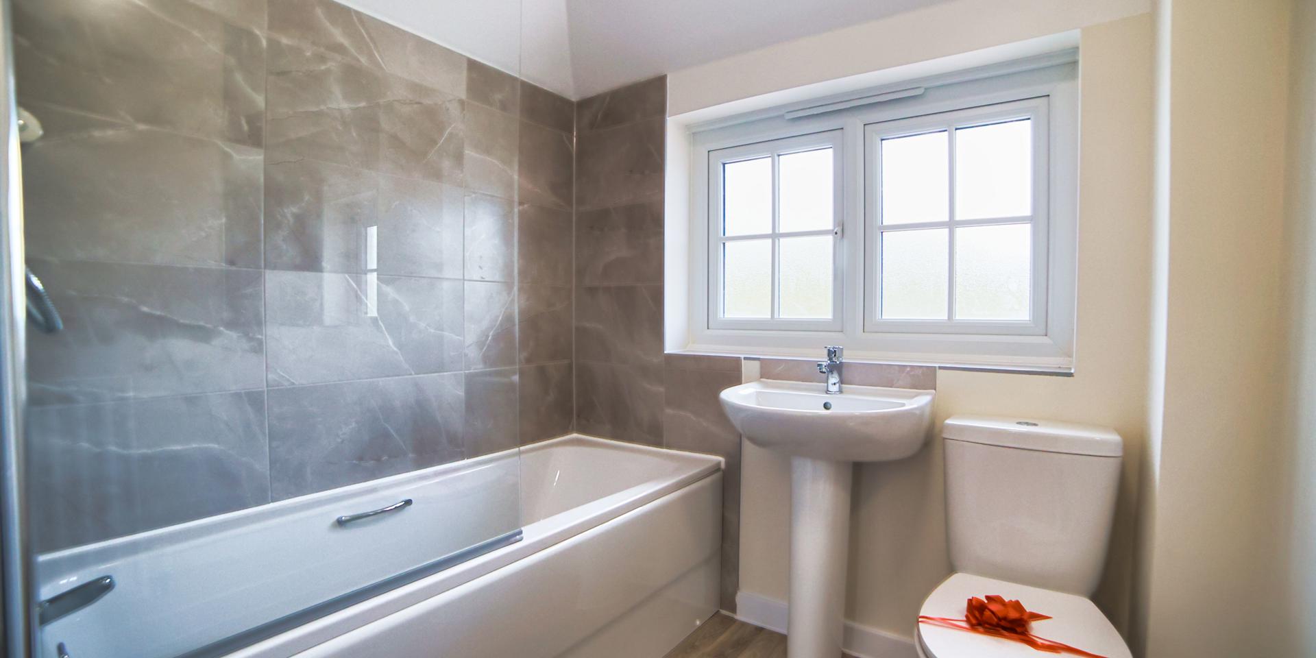 The bathroom with its white bathroom suite, bath and shower over the bath