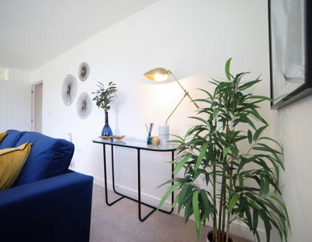 A console table in the living area with a lamp, vase and accessories on it.