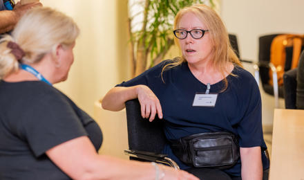 residents voice and scrutiny panel member talking to a member of staff.