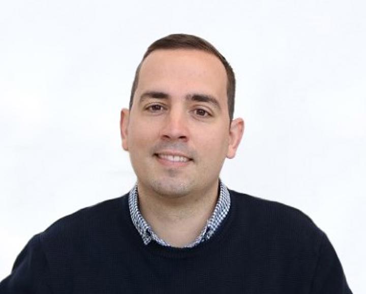 Headshot of Chris Ellmore - member of the board at Hightown. He is wearing a black jumper with a blue shirt underneath.