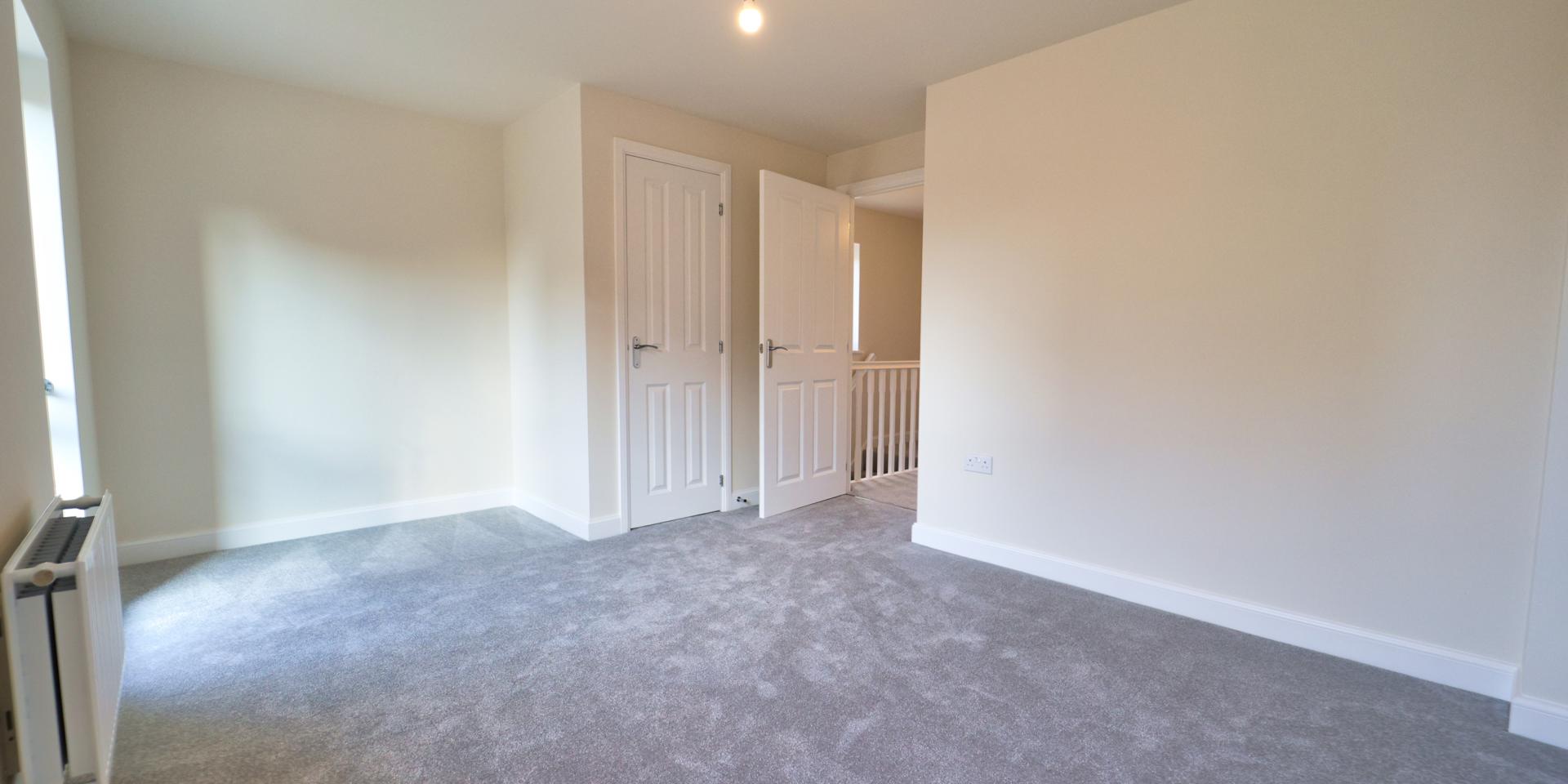 A large window and built-in storage cupboard in this double bedroom