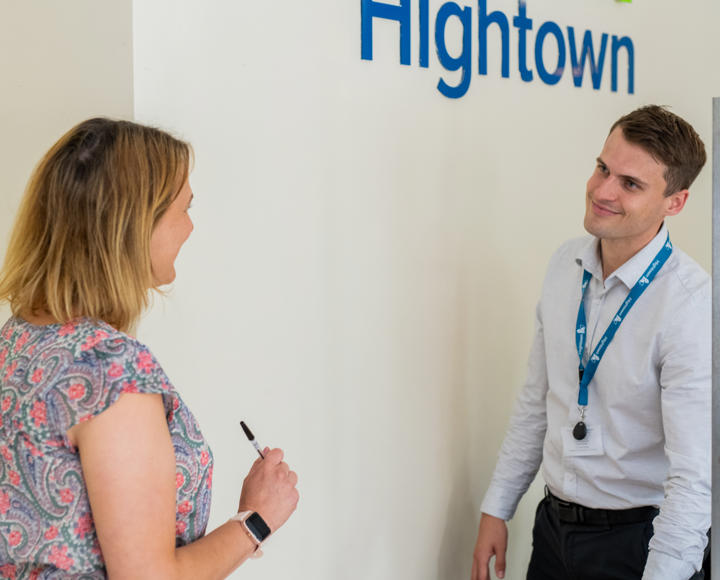 A member of staff talking to a resident at reception in Hightown's head office
