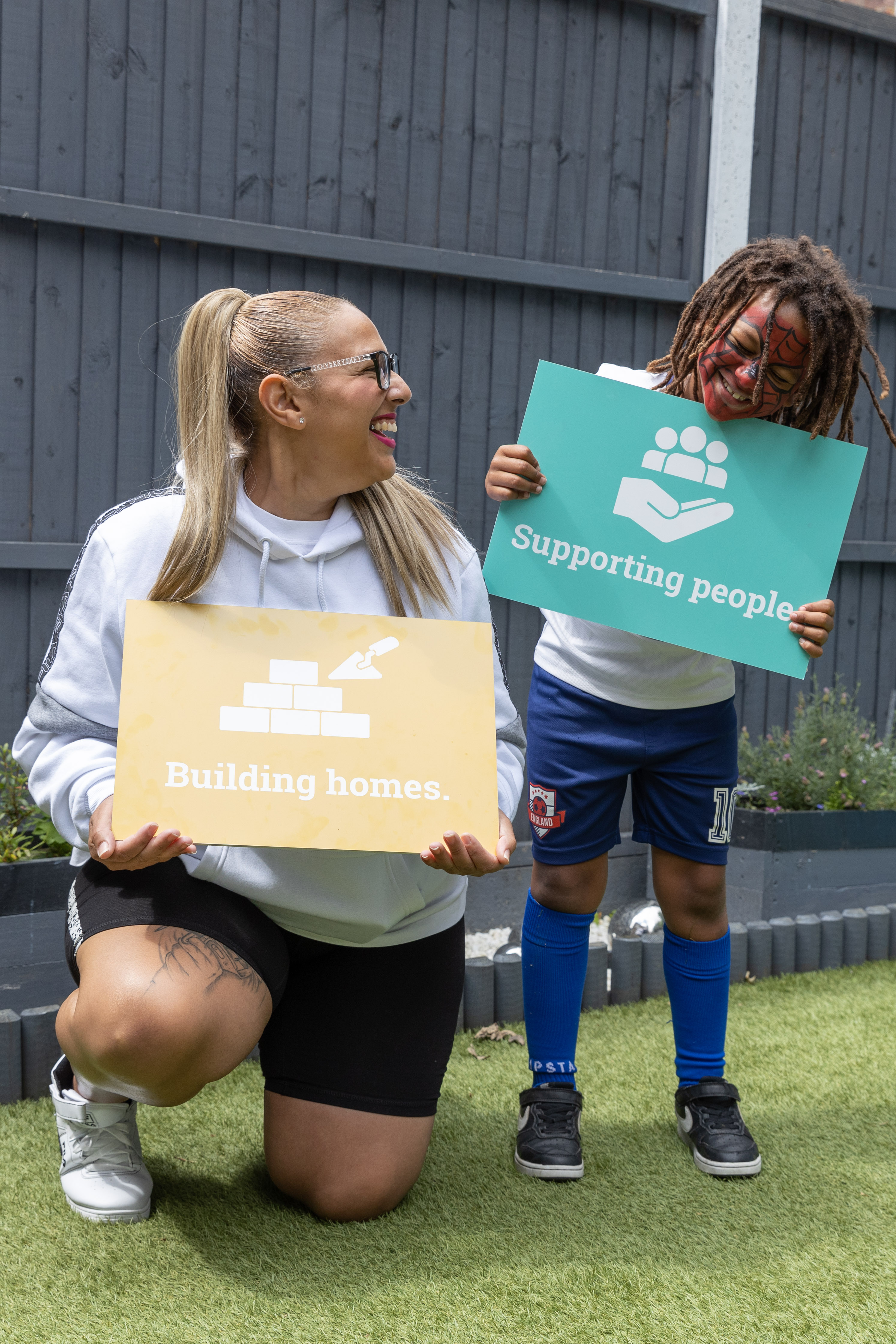 Residents holding boards showing Hightown's mission statement 'Building homes. Supporting people'