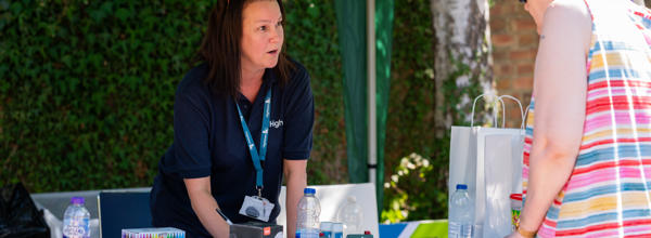 A member of staff talking to a resident at a open day in the summer.