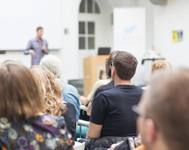 People sitting and listening to a man talk at a conference