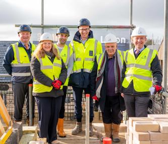 Staff from Hightown, Hill Group and Luton Council standing in hi-vis jackets on a building site