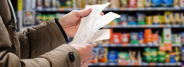 Someone holding a lot of receipts in a supermarket, showing the impact of the cost of living crisis 