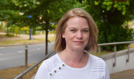 Director of housing. She is wearing a white t-shirt and has shoulder length blonde hair and green eyes. 