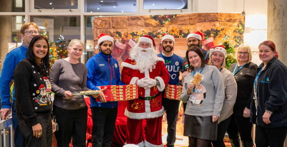 Hightown staff, Tesco staff and Santa smiling and holding mince pies