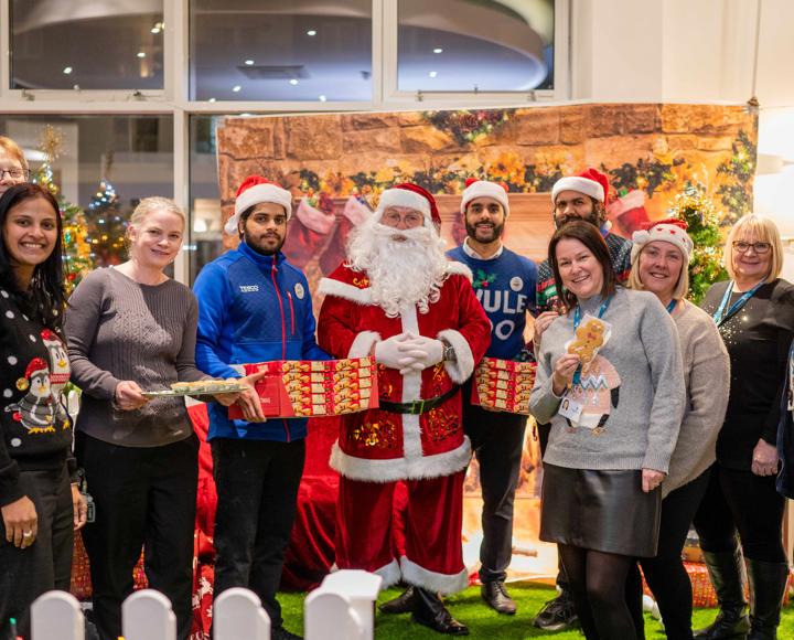 Hightown staff, Tesco staff and Santa smiling and holding mince pies
